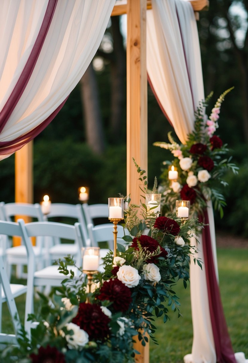 A romantic outdoor wedding ceremony with burgundy floral arrangements, draped fabric, and candlelit ambiance