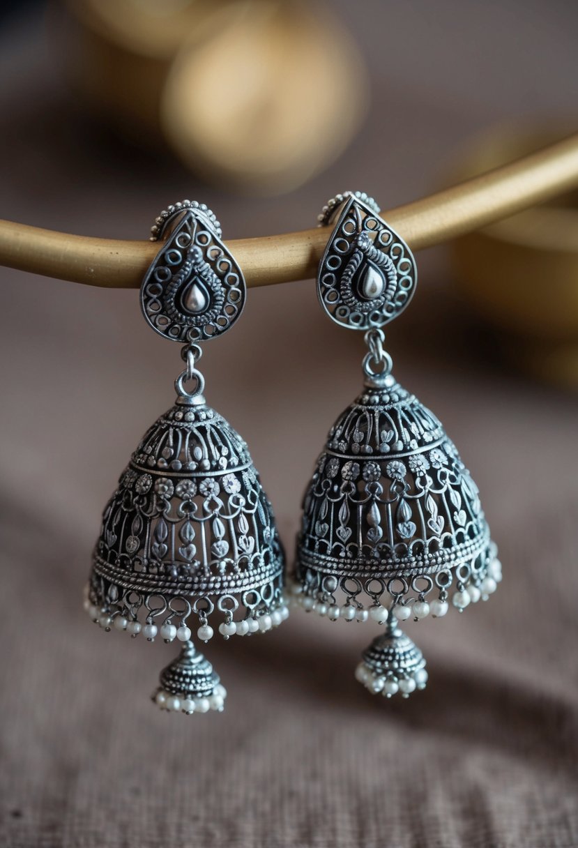 A pair of intricately designed silver oxidized jhumkas, adorned with delicate filigree and dangling beads, inspired by traditional Indian bridal jewelry