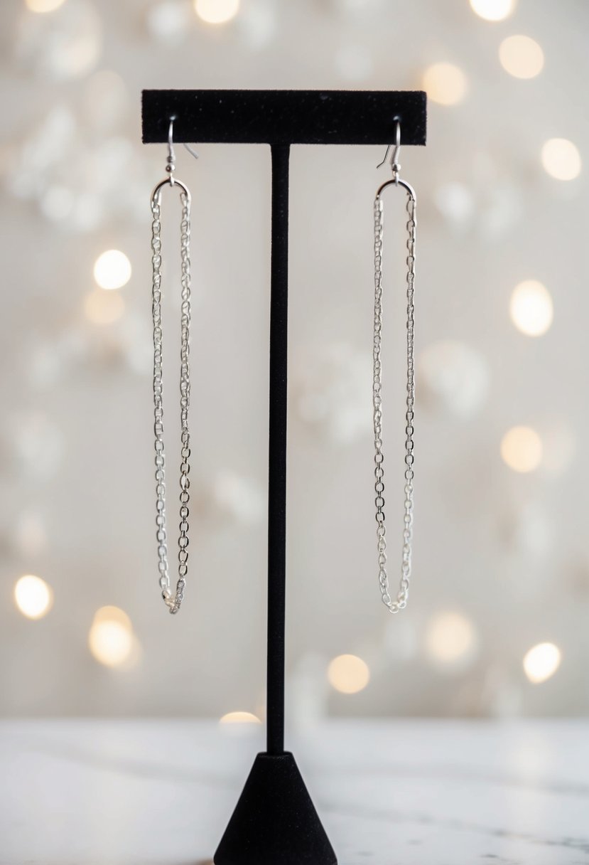 A pair of minimalist chain huggie earrings hanging from a stand, with a soft, elegant background