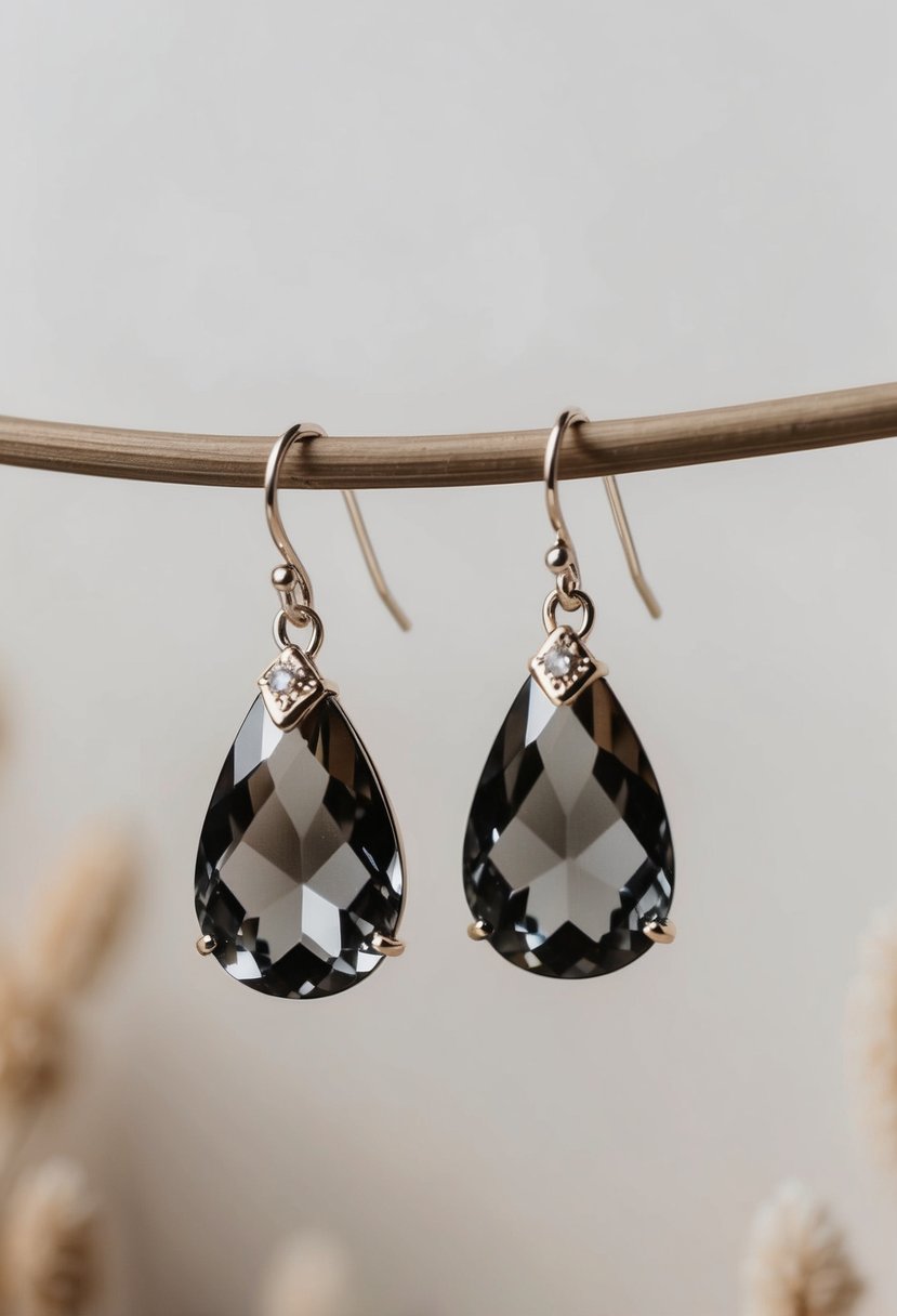 Two teardrop-shaped earrings made of smoky gray quartz crystals, with delicate handcrafted details, displayed against a soft, neutral background